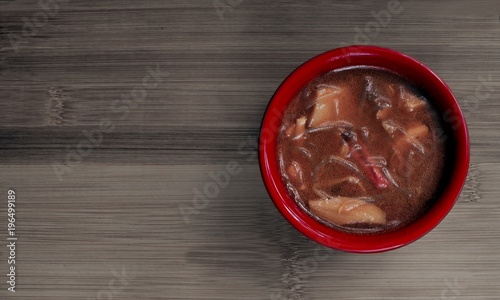 Leckere Bihun Suppe in einer roten Schale, serviert auf einem Bambus Brett. 