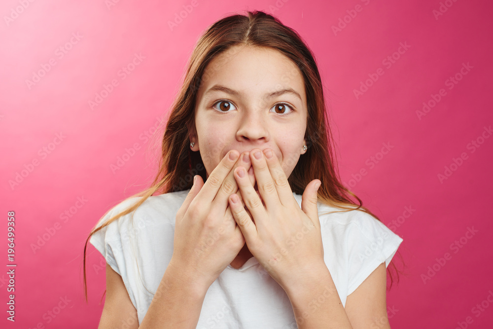 Portrait of surprised girl on a pink background