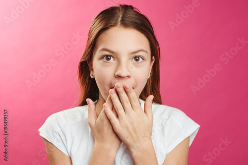 Portrait of surprised girl on a pink background