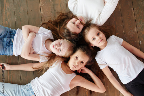 The children go in a circle. Four girls on the wooden floor, top view.