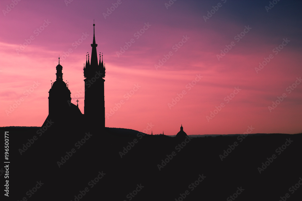 Black silhouette St. Mary Basilica in Krakow and panorama of the city center against a background of sunset and a fantastic red purple sky