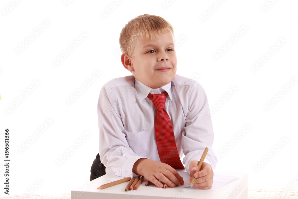 Handsome schoolboy is looking at camera and leaning on the table while drawing Handsome schoolboy is looking at camera and leaning on the table while drawing