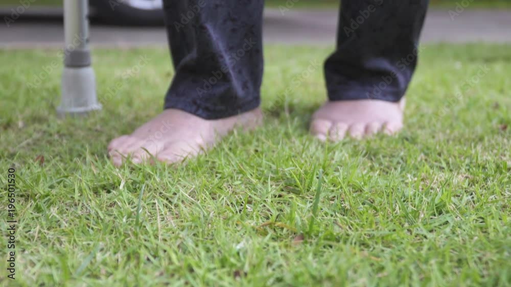 Elderly woman walking barefoot therapy on grass in backyard. Elderly woman walking barefoot therapy on grass in backyard.
