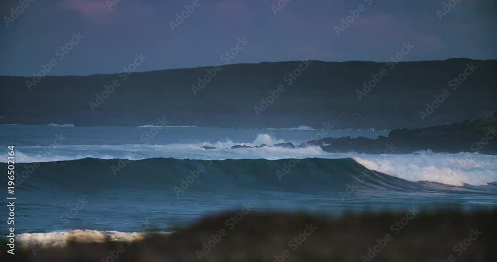 Waves crash against a rocky shore in golden light. Waves crash against a rocky shore in golden light.