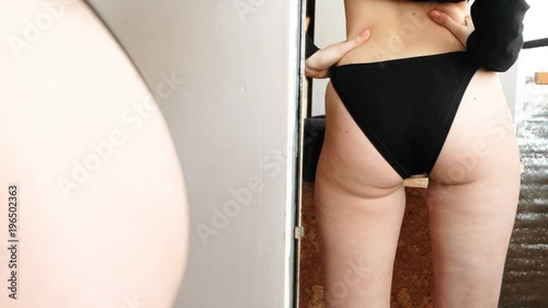 Cellulite in women booty and legs. Closeup ass women in front of the mirror in the blue trunks.