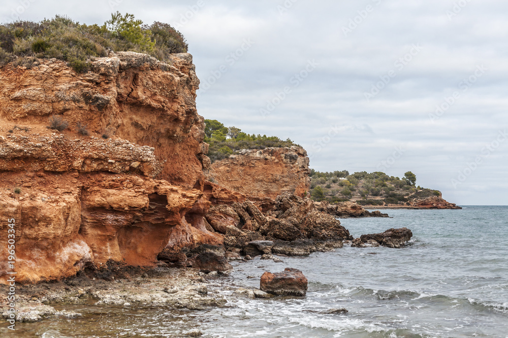 Mediterranean cliffs, orange rocks, coastilne of Ampolla de Mar, Costa Daurada, province Tarragona, Catalonia, Spain.