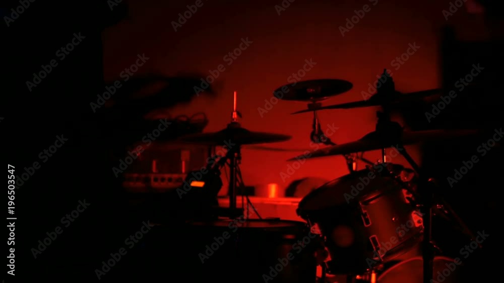 Unrecognizable male drummer silhouette playing the drums. Red light, low key. Entertainment and art concept