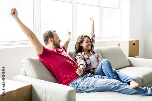 Couple sitting together on sofa at home happy to move from home