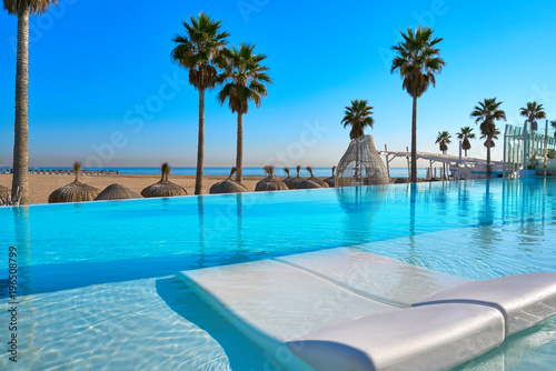Resort infinity pool in a beach with palm trees