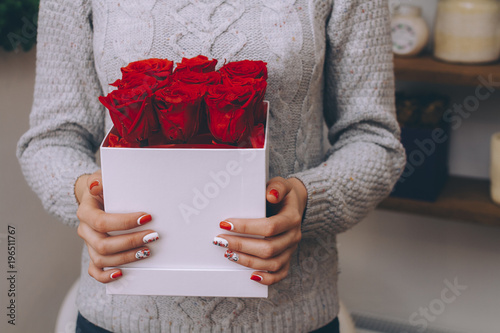 Bouquet of red roses in a gift box in female hands