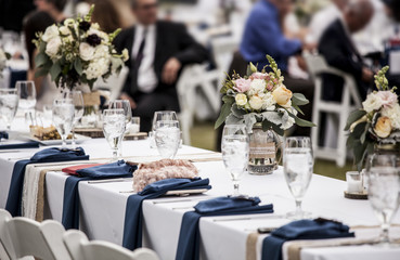 Table set up for wedding reception with people out of focus in background.