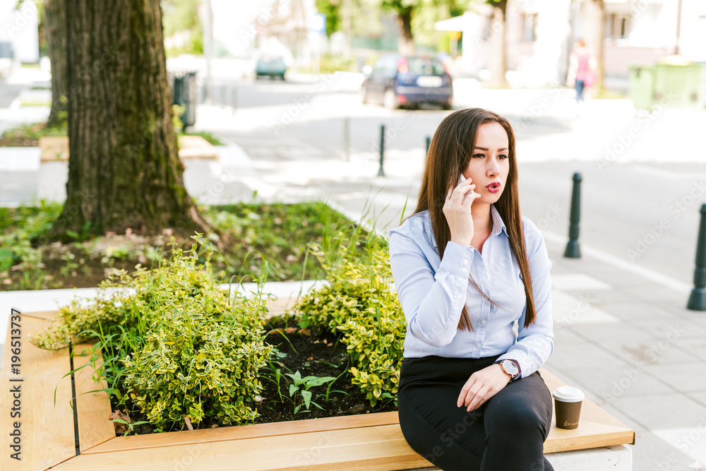Fototapeta premium Young beautiful businesswoman drinks coffee and use cellphone