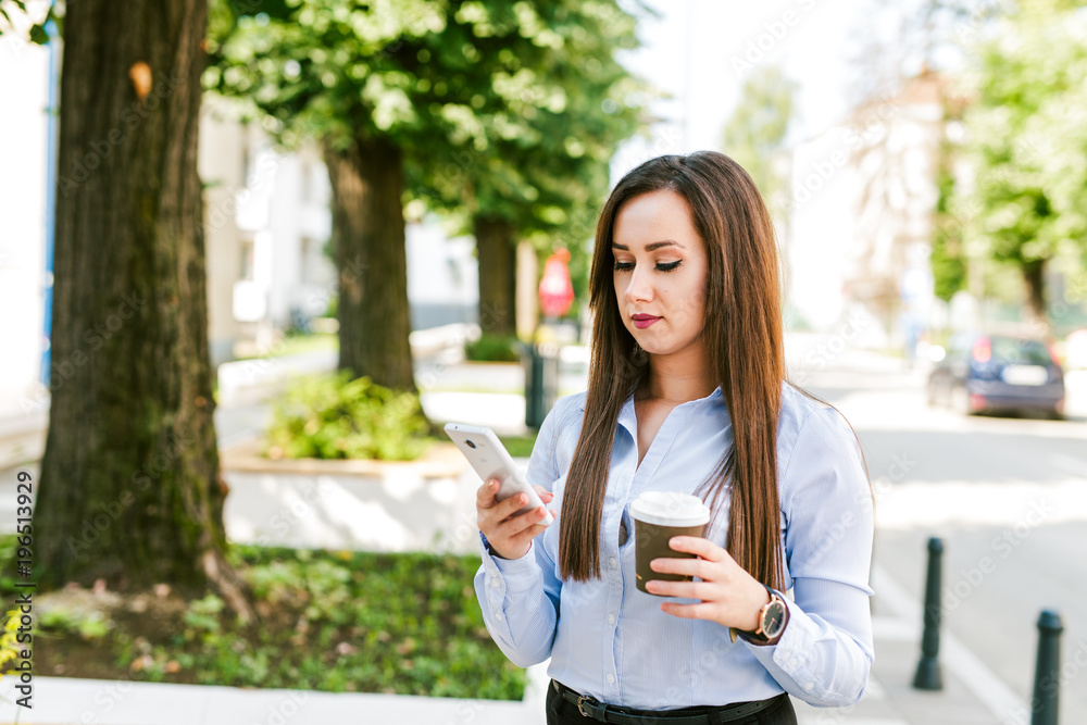 Young beautiful businesswoman drinks coffee and use cellphone Young beautiful businesswoman drinks coffee and use cellphone