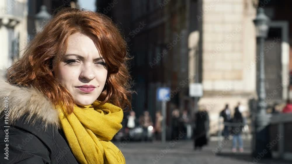 beautiful woman with red hair in the city looking at the camera beautiful woman with red hair in the city looking at the camera