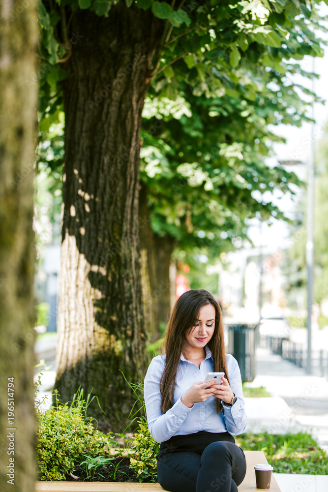Young beautiful businesswoman drinks coffee and use cellphone Young beautiful businesswoman drinks coffee and use cellphone