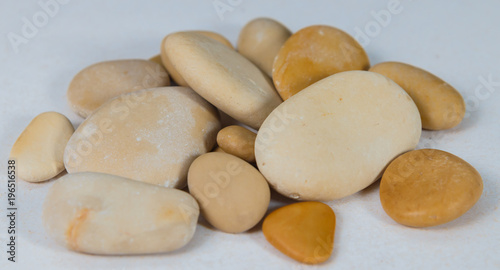 pebbles. clean white brown black pebbles isolated. the pebbles are on white or brown sand. small and large are visible