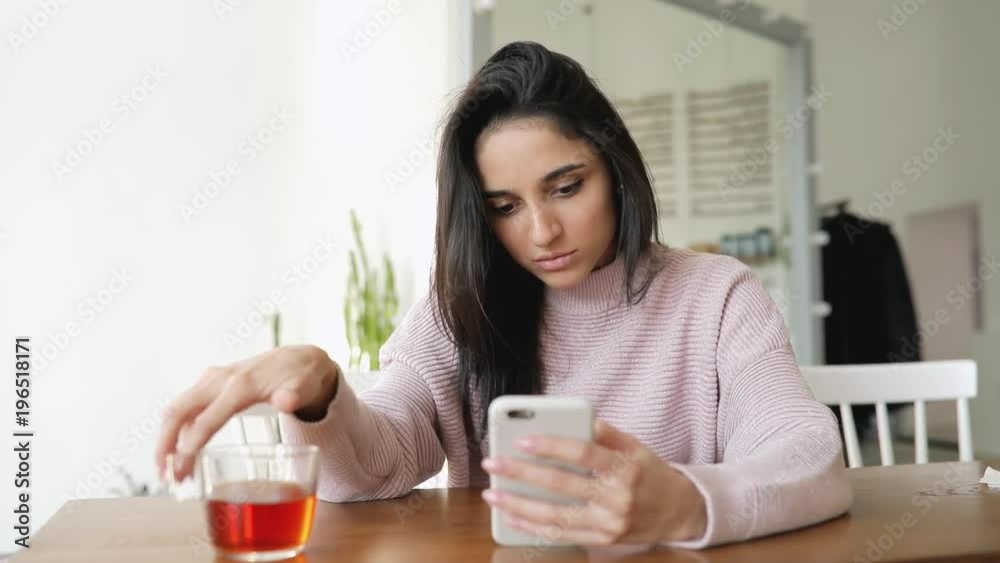Beautiful woman using smartphone app sitting in a cafe rotating cup Beautiful woman using smartphone app sitting in a cafe rotating cup
