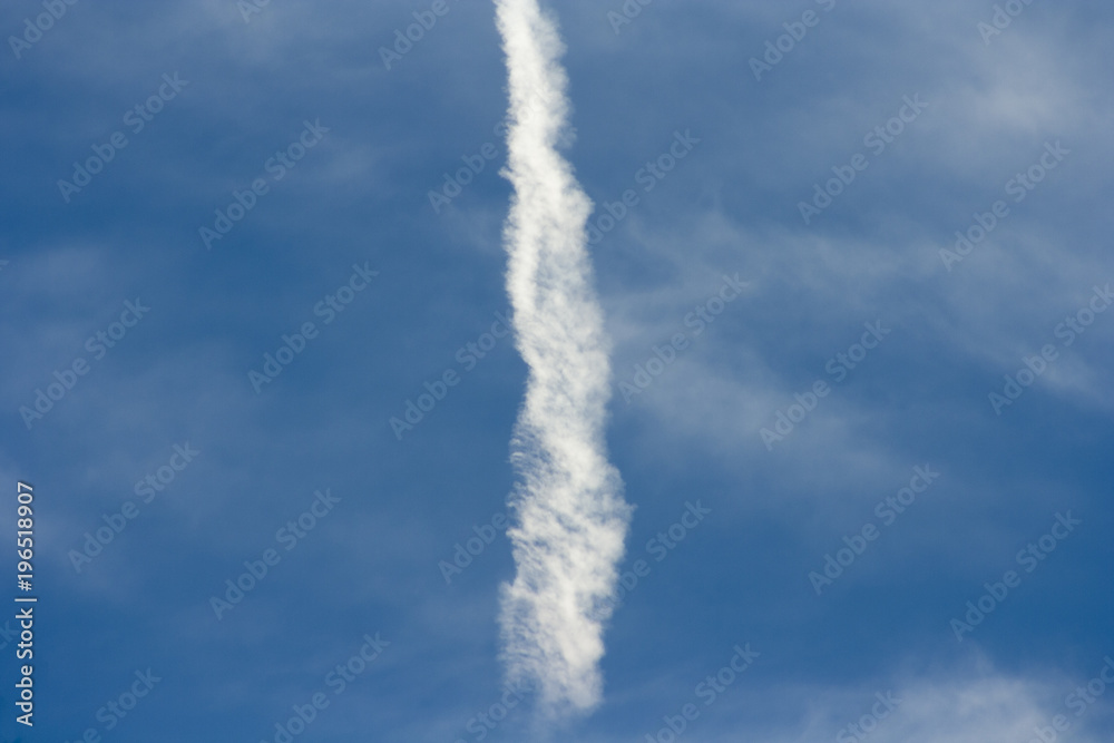 A beautiful blue sky with a dispersed streak of a flying airplane..