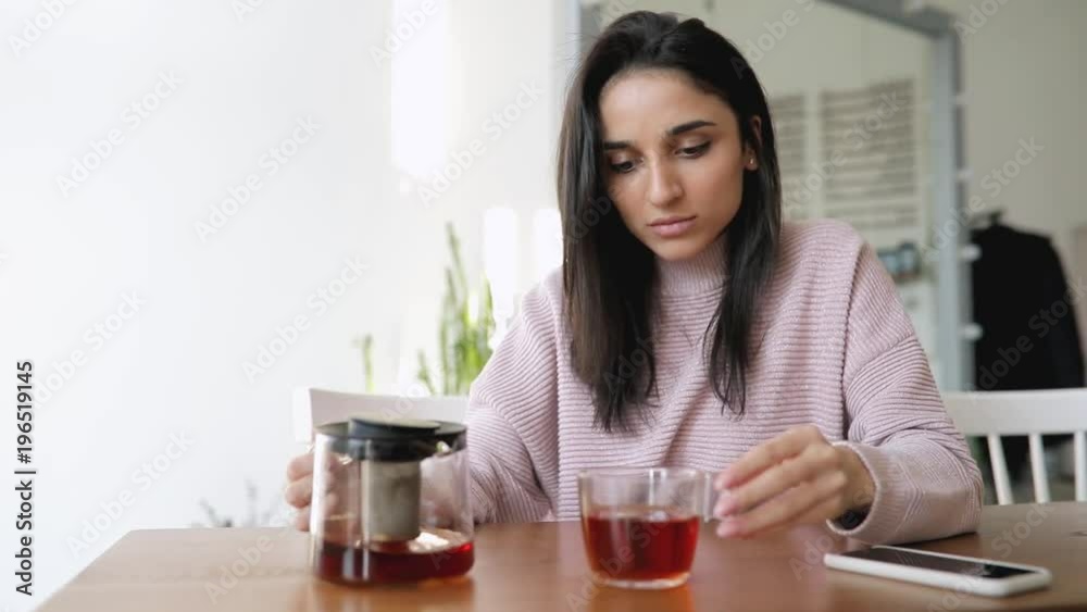 Beautiful woman pouring tea from kettle into glass in a cafe Beautiful woman pouring tea from kettle into glass in a cafe