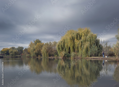 A autumn fishing spot on the shores of the lake with willows