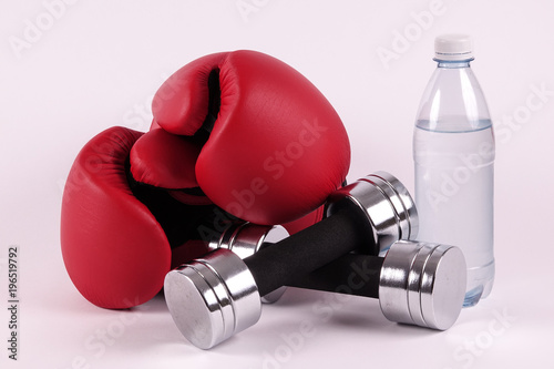 A pair of boxing gloves and dumbbells and a bottle of water. Ready for a hard fight workout. Concepts for martial arts, boxercise, gym and workout, etc. photo