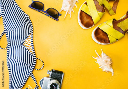 Accessories a traveler on a yellow background with the swimsuit, camera and sunglasses. Top view travel or vacation concept.
