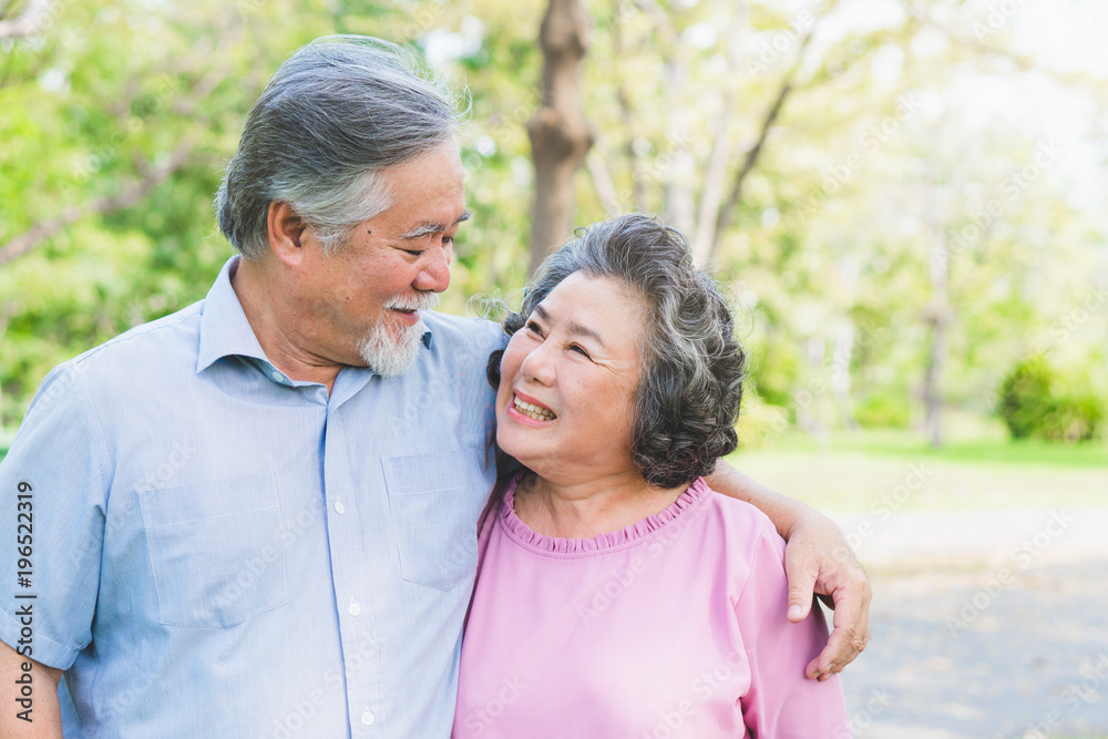 Romantic asian healthy senior couple looking each other eyes and relaxing in the park together. Have a copy space for your text.