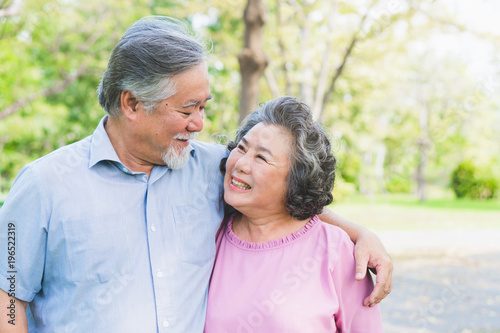 Romantic asian healthy senior couple looking each other eyes and relaxing in the park together. Have a copy space for your text.
