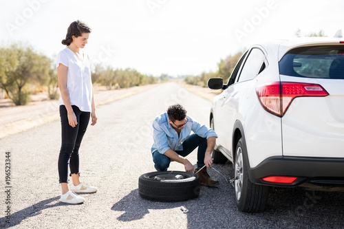 фотографія Couple changing wheel on a roadside