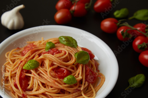 spaghetti dish with tomato sauce and basil on black background