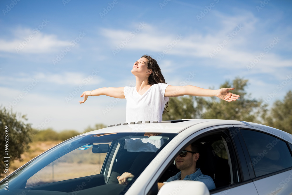 Woman enjoying the fresh air while boyfriend drive car
