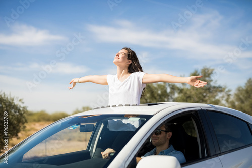 Woman enjoying the fresh air while boyfriend drive car