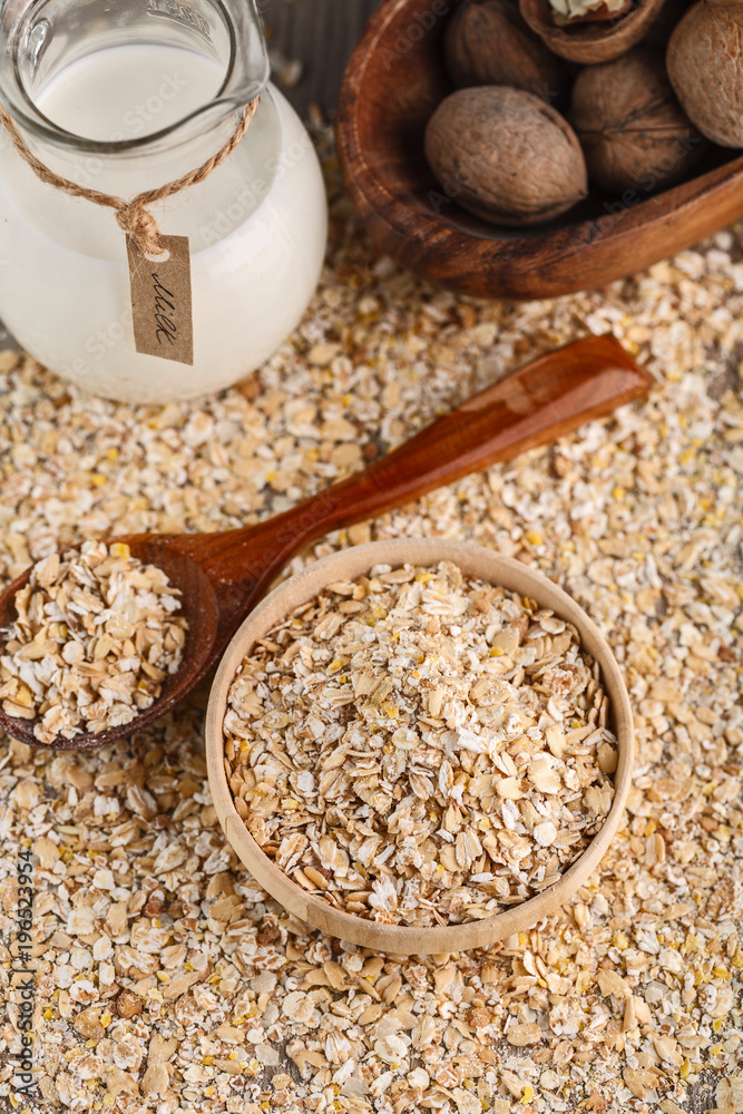Dry rolled oatmeal in wooden bowl and wooden spoon on oatmeal background. Dry rolled oatmeal in wooden bowl and wooden spoon on oatmeal background.