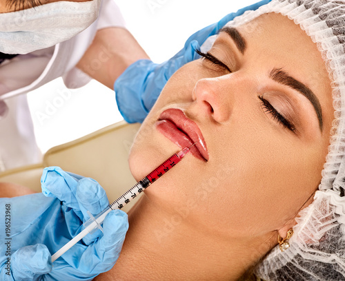 Filler injection for female forehead face. Plastic aesthetic facial surgery in beauty clinic. Doctor in medical gloves with syringe injects lips augmentation. Bottox injections.