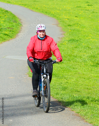 Overweight woman slimming on bicycle. Active people enjoying summer holidays on countryside. 