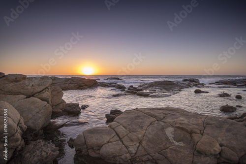 The sun sets over the horizon as evening waves roll upon Surfers Point near Margaret River in Western Australia.