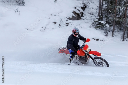 Motorcyclist on a crossover motorcycle rides in the snow. Turn of wheels a spray of snow