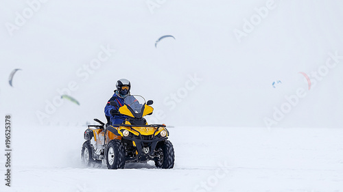 ATV rides in the snow. From the wheels a spray of snow. Place for text.