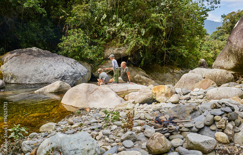 Father and sons relaxing on rocks beside water, Ventilla, La Paz, Bolivia, South America