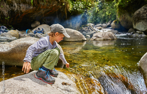 Boy  crouching on rock beside water pool, Ventilla, La Paz, Bolivia, South America