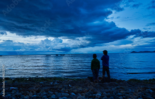 Two boys standing beside lake, looking at view, rear view, Copacabana, Oruro, Bolivia, South America
