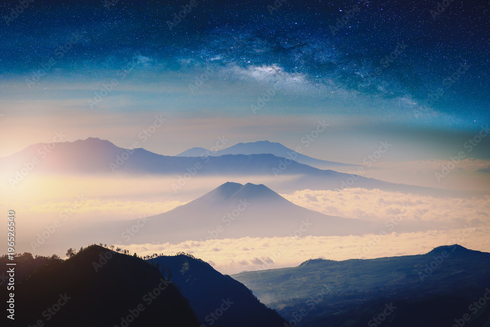 Mountain range in fog with sunlight and milky way galaxy.
