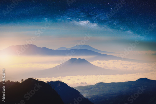 Mountain range in fog with sunlight and milky way galaxy. © nuttawutnuy