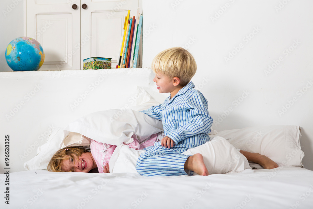 Boy and female twin play fighting on bed Boy and female twin play fighting on bed