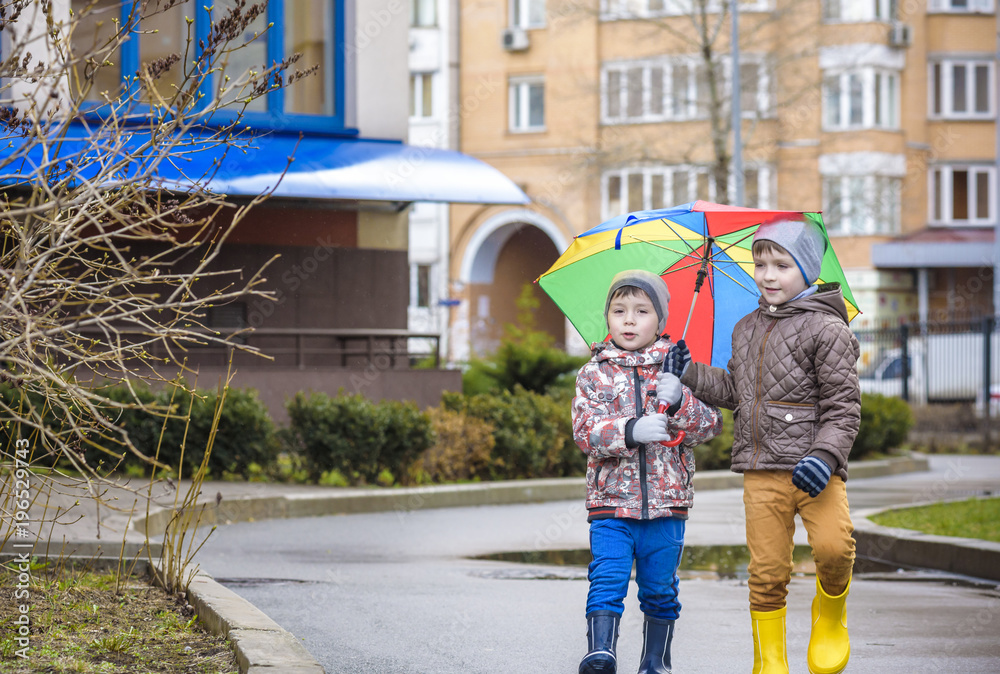 Obraz premium Two little boys, squat on a puddle, with little umbrellas