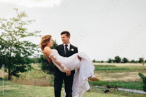 Young groom carrying his beautiful wife photo