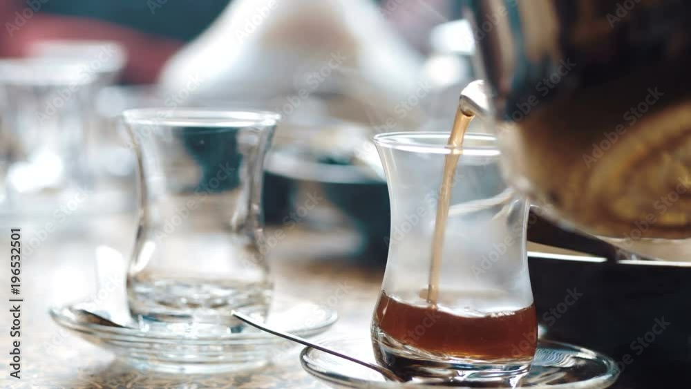 The waiter pours the eastern tea in cups. The waiter pours the eastern tea in cups.