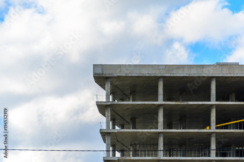 Reinforced concrete skeleton of an unfinished building against the background of a cloudy sky