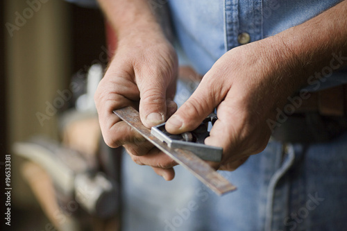 Hands of a male builder holding a measuring tool. photo