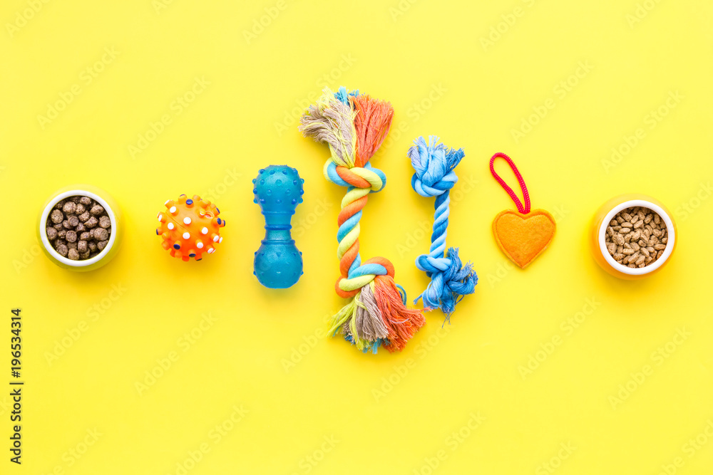 toys for pets and dry food on yellow background top view space for text